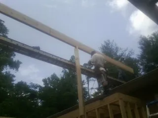 Carpenter setting a ridge beam over a new addition frame — Ice Dam Removal by Roofing Brothers in Brunswick